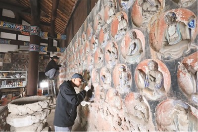 2023年3月31日,大足石刻小佛湾修复现场,修复人员正在对石窟造像进行清理。小佛湾石窟保护修复工程于2019年6月启动,目前已完成整个工程量的六成。 黄 舒摄(人民图片)