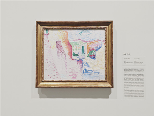 马蒂斯《科利尤尔,太阳街》。马蒂斯在科利尤尔可以俯瞰阿瓦尔港海滩的地点画下了这幅作品,画家通过色彩构建风景,表现了科利尤尔在夏季阳光照射下的饱和色彩,房子是粉色,百叶窗是蓝色,屋顶覆盖着橙色的瓦片,富有变化的蓝铺就石板路,天空是近乎透明的蓝,山脊则是位于远处的粉红。经过此前对点彩派风格的尝试之后,马蒂斯意识到留白可以使纯色并置,创造空间,并将它们组织起来。在这幅作品中,正是色彩而非线条构建了整幅画作。没有画出的海滩以及笔触之间的大量空白传达出未完成感,令人耳目一新。《科利尤尔,太阳街》因此被视为一幅革命性的作品,它具有水彩的轻盈感,开辟了绘画的新方法,为幻想、光芒和“寂静”提供了同等空间。