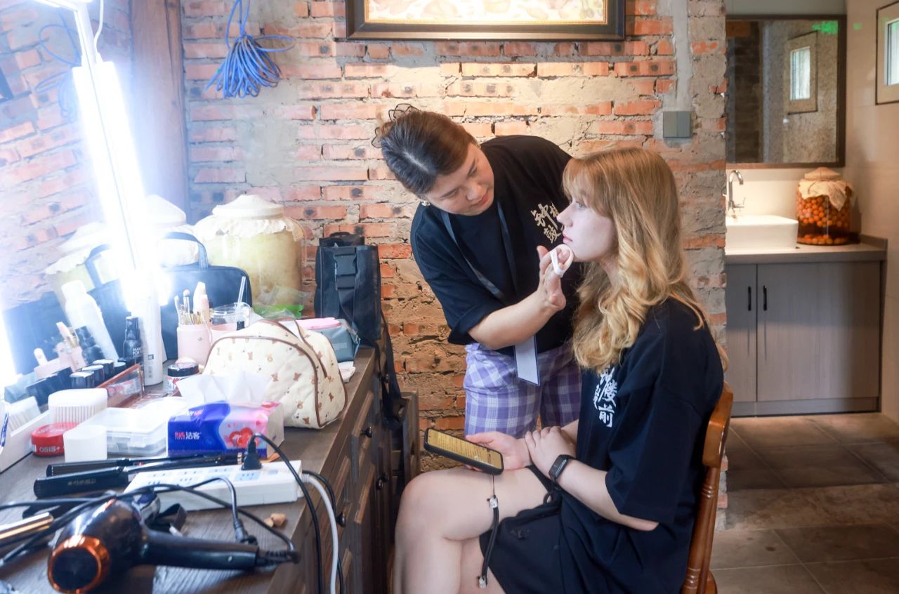 2025年6月30日,百集微短剧《钟鼓楼前》在北京鼓楼前开机。图为俄罗斯籍女演员玛利亚在开拍前化妆。 中新社记者 贾天勇 摄